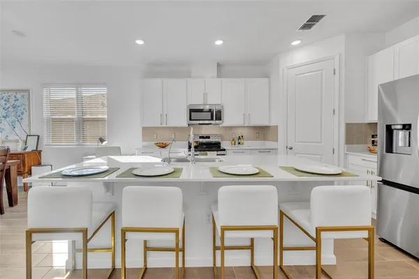 a kitchen with stainless steel appliances granite countertop a table chairs microwave and cabinets