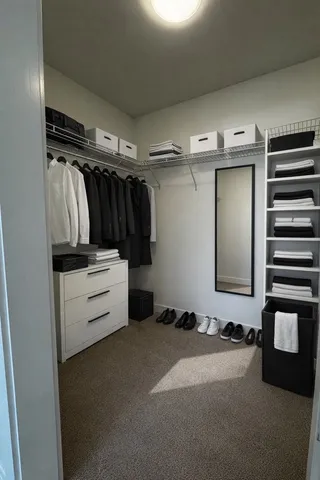 a view of walk in closet with clothes and shoes