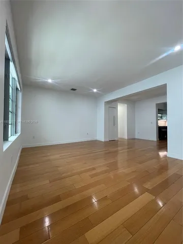 a view of an empty room with window and wooden floor