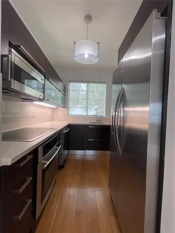 a kitchen with stainless steel appliances granite countertop a refrigerator a sink and wooden floor