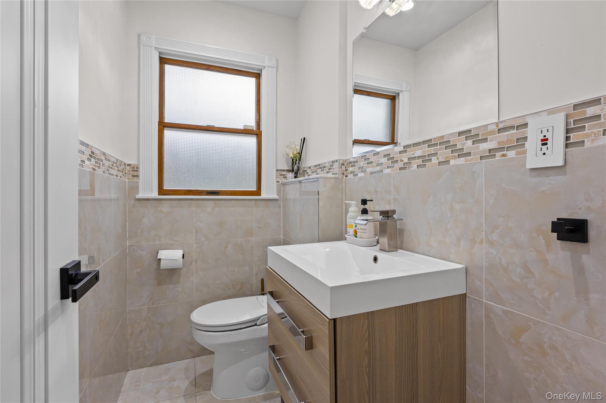 8 Willow Road New Hyde Park, NY 11040 - Photo 12 of 34 a bathroom with a sink a toilet and mirror