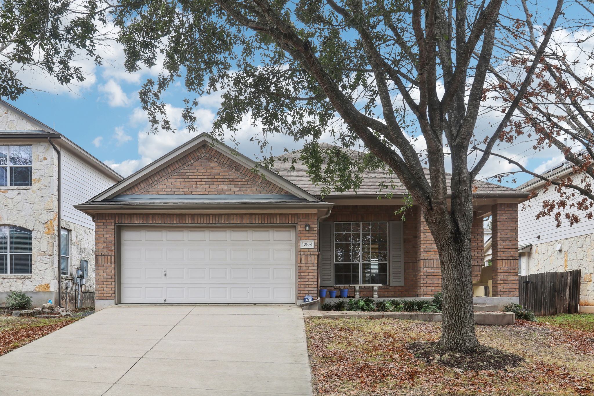 View of front of home with brick siding, concrete driveway, covered porch, and a garage