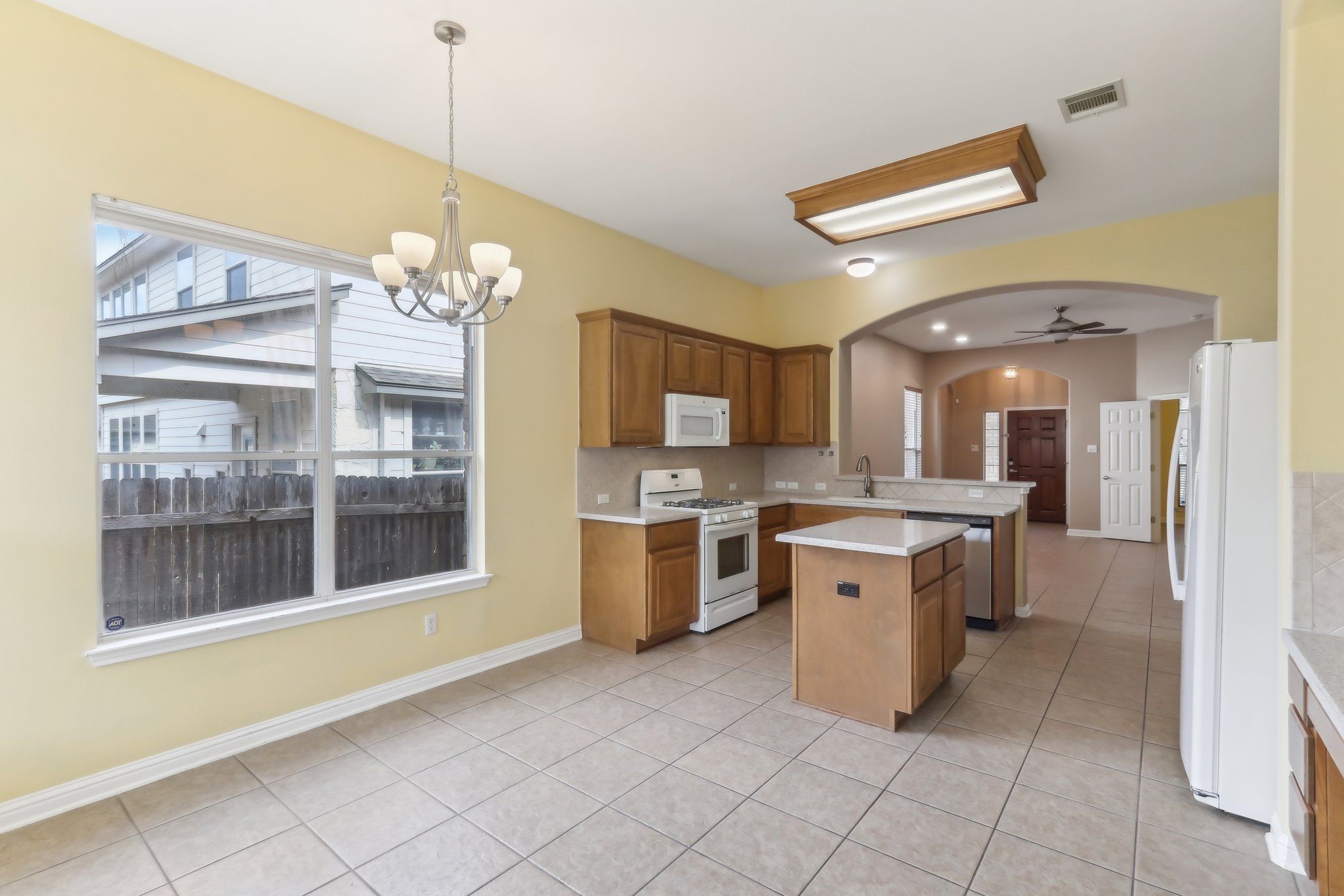 10108 Channel Island Drive Austin, TX 78747 - Photo 10 of 36 Kitchen featuring arched walkways, a peninsula, a kitchen island, white appliances, and light tile patterned floors