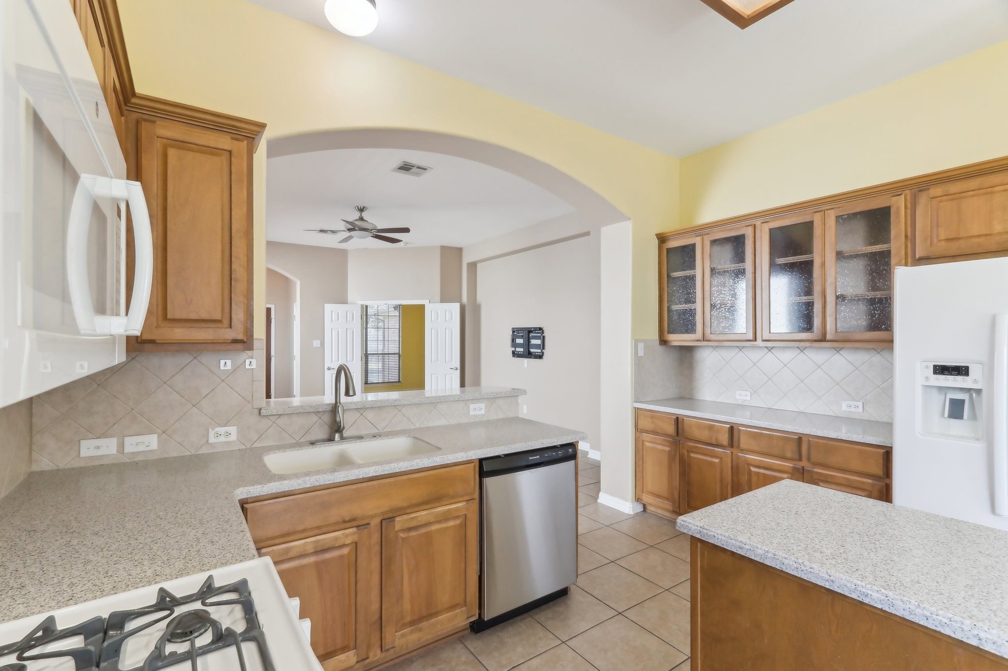 10108 Channel Island Drive Austin, TX 78747 - Photo 11 of 36 Kitchen with light stone counters, white appliances, wood finish cabinetry, a ceiling fan, and decorative backsplash