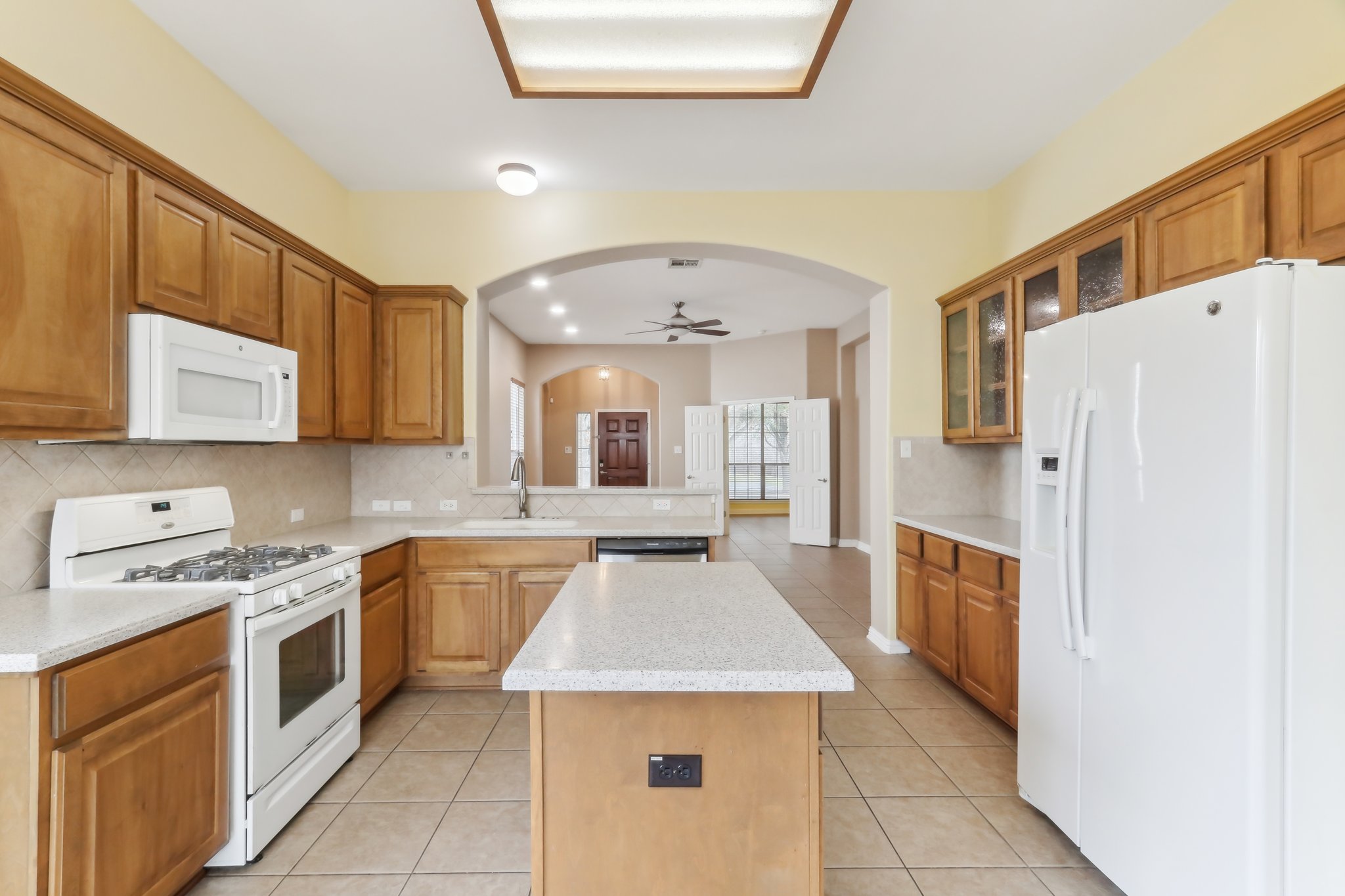 10108 Channel Island Drive Austin, TX 78747 - Photo 13 of 36 Kitchen featuring white appliances, arched walkways, ceiling fan, wood finish cabinets, and recessed lighting