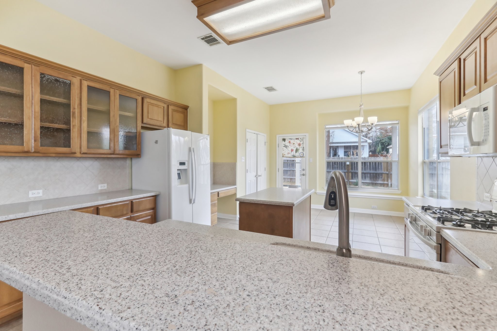 10108 Channel Island Drive Austin, TX 78747 - Photo 15 of 36 Kitchen featuring backsplash, a kitchen island, glass insert cabinets, white appliances, and wood finish cabinetry