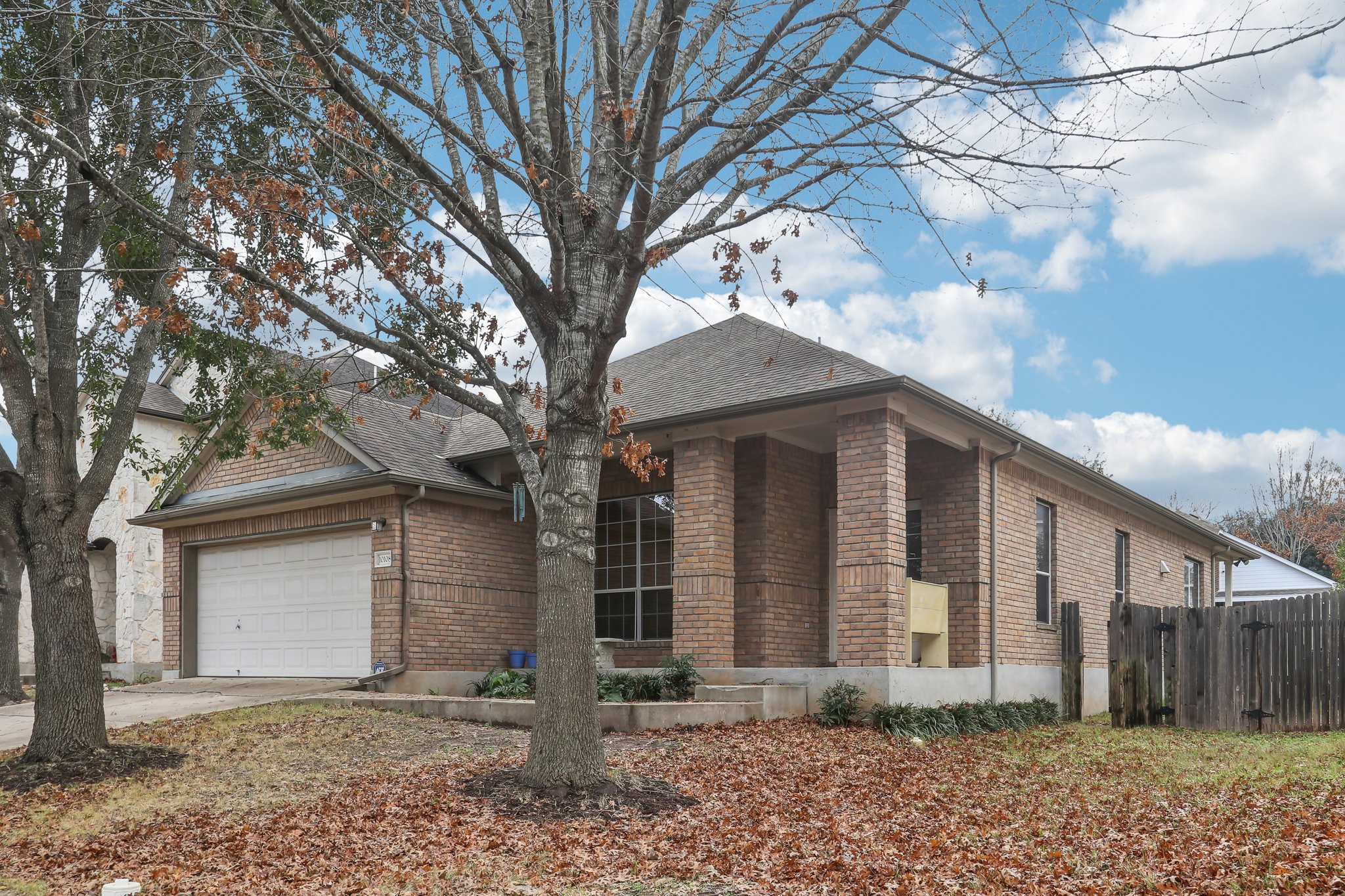 10108 Channel Island Drive Austin, TX 78747 - Photo 2 of 36 View of front facade with concrete driveway, brick siding, a shingled roof, and a garage