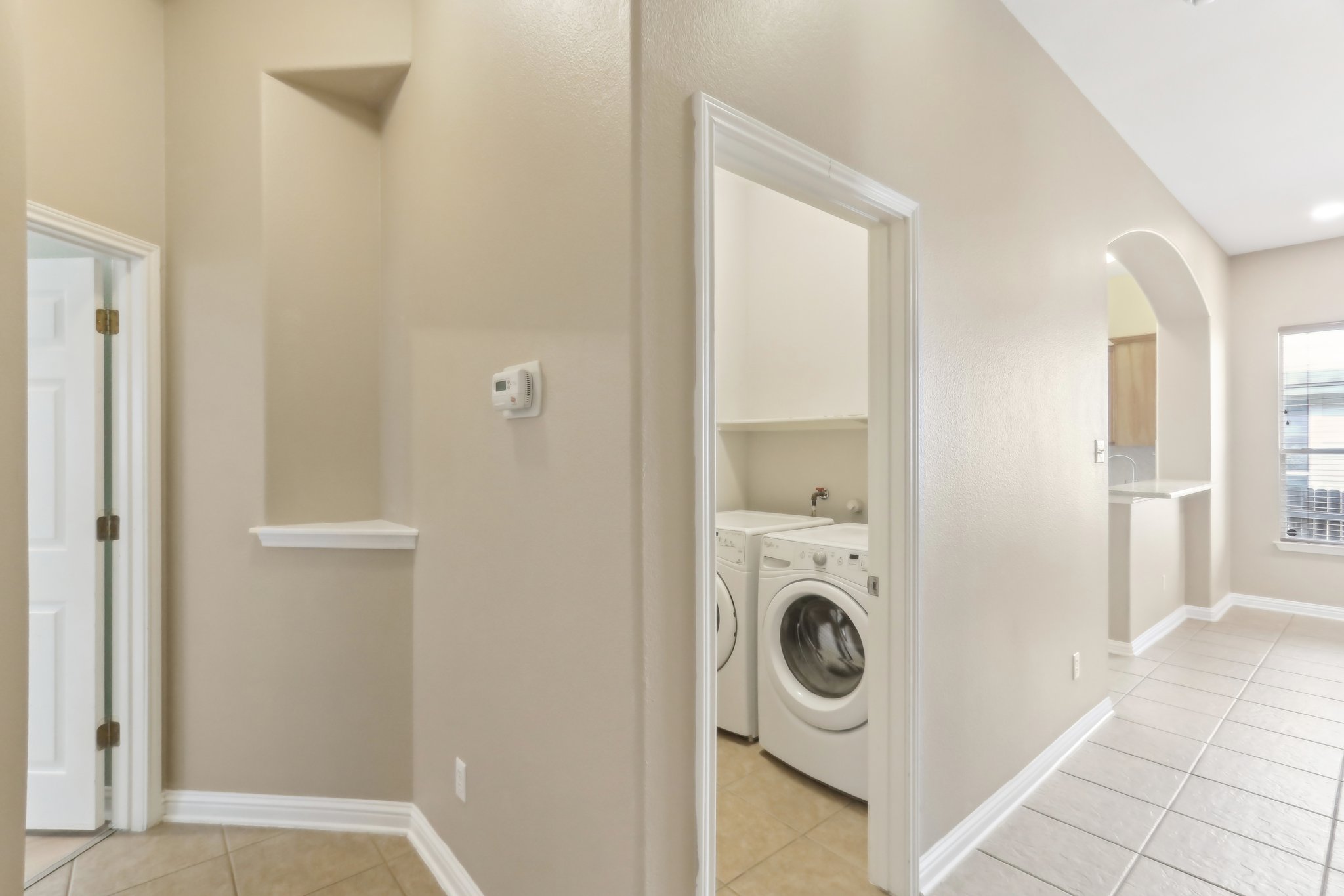 10108 Channel Island Drive Austin, TX 78747 - Photo 25 of 36 Laundry area with washing machine and clothes dryer, light tile patterned floors, and arched walkways
