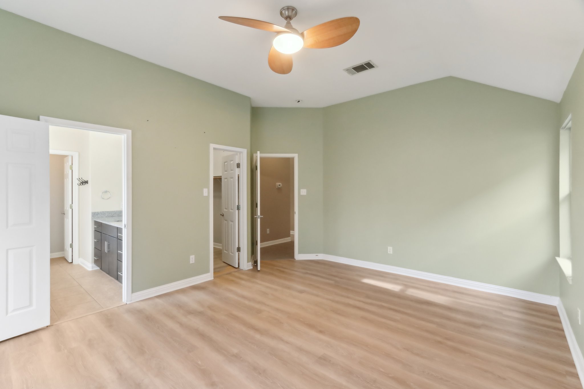 10108 Channel Island Drive Austin, TX 78747 - Photo 27 of 36 Unfurnished bedroom featuring a walk in closet, vaulted ceiling, light wood-style flooring, a ceiling fan, and ensuite bathroom