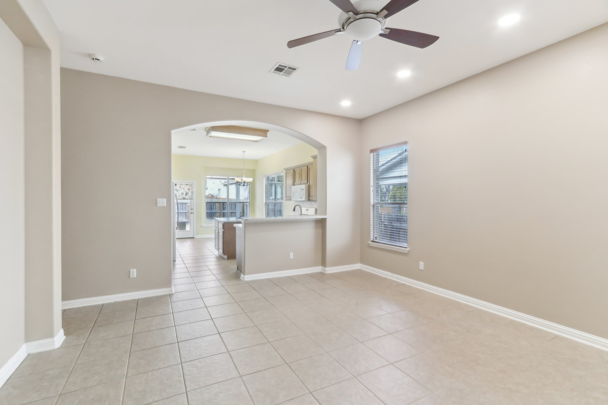 10108 Channel Island Drive Austin, TX 78747 - Photo 5 of 36 Empty room featuring arched walkways, a ceiling fan, light tile patterned floors, and a chandelier