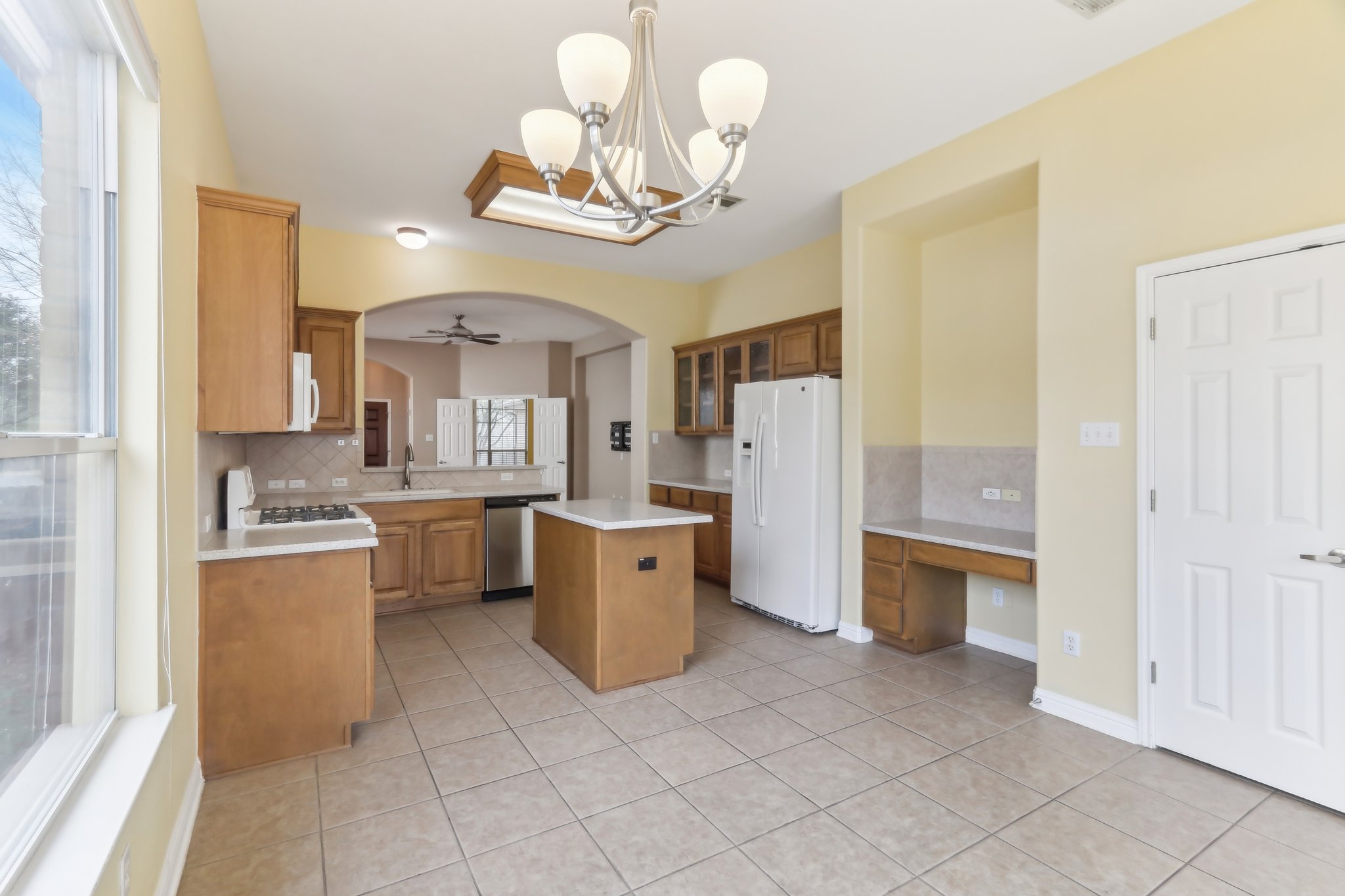 10108 Channel Island Drive Austin, TX 78747 - Photo 9 of 36 Kitchen featuring tasteful backsplash, a center island, white appliances, glass insert cabinets, and light countertops