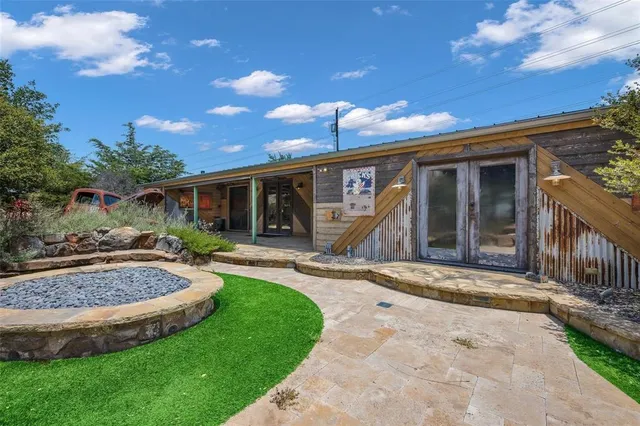 a backyard of a house with table and chairs under an umbrella