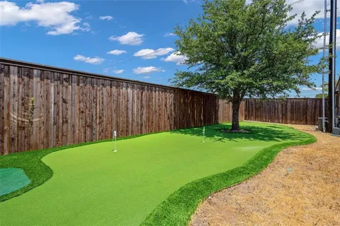 a backyard of a house with table and chairs under an umbrella