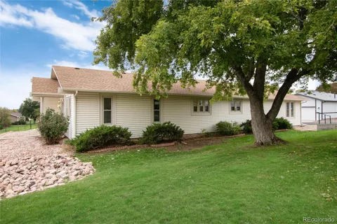 a view of a house with a small yard and a large tree