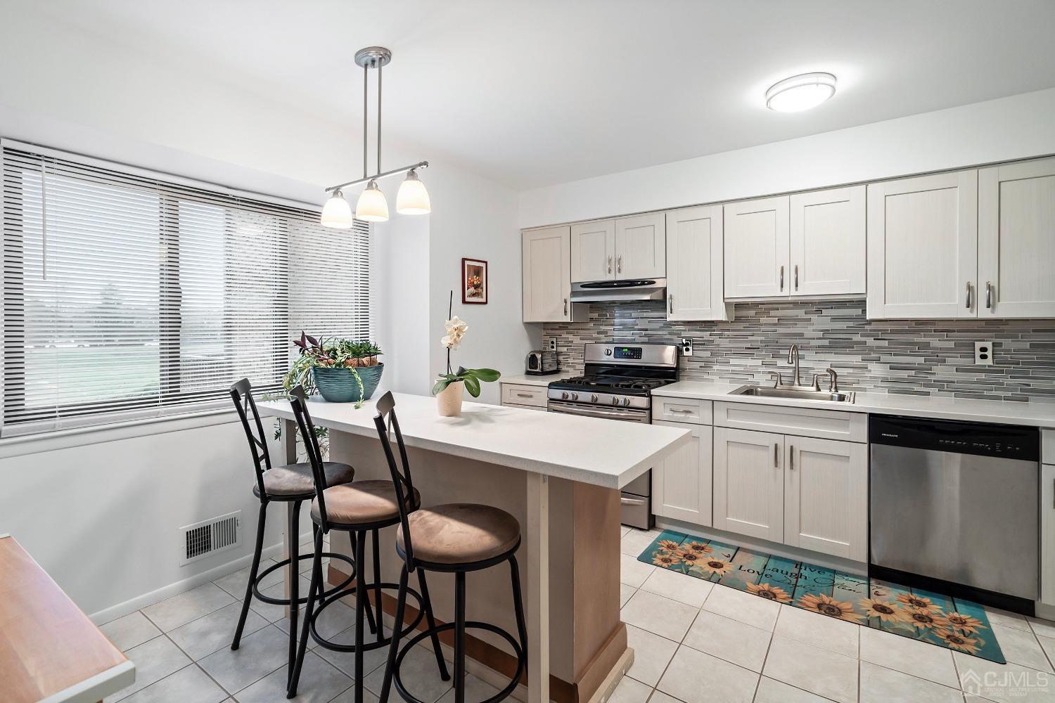 606 Robin Road Hillsborough, NJ 08844 - Photo 6 of 20 a kitchen with stainless steel appliances kitchen island granite countertop a sink a stove a dining table and chairs