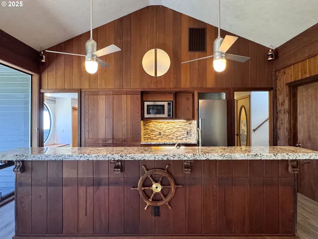 a large kitchen with stainless steel appliances granite countertop a stove a sink and a wooden cabinets