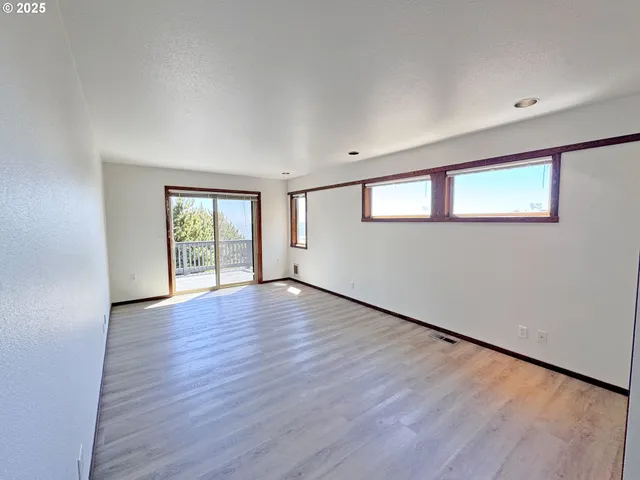 a view of an empty room with window and wooden floor