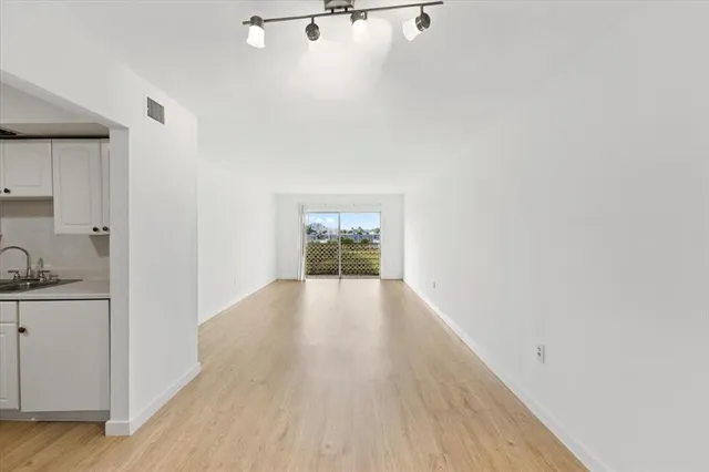 a view of a kitchen with wooden floor and cabinets