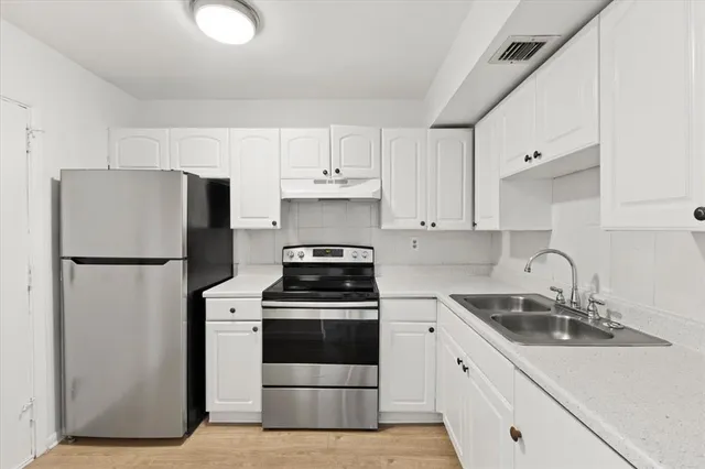 a kitchen with a refrigerator sink and white cabinets
