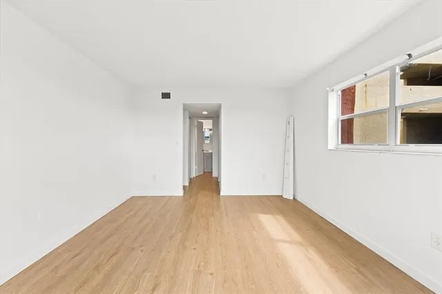 a view of empty room with wooden floor and windows
