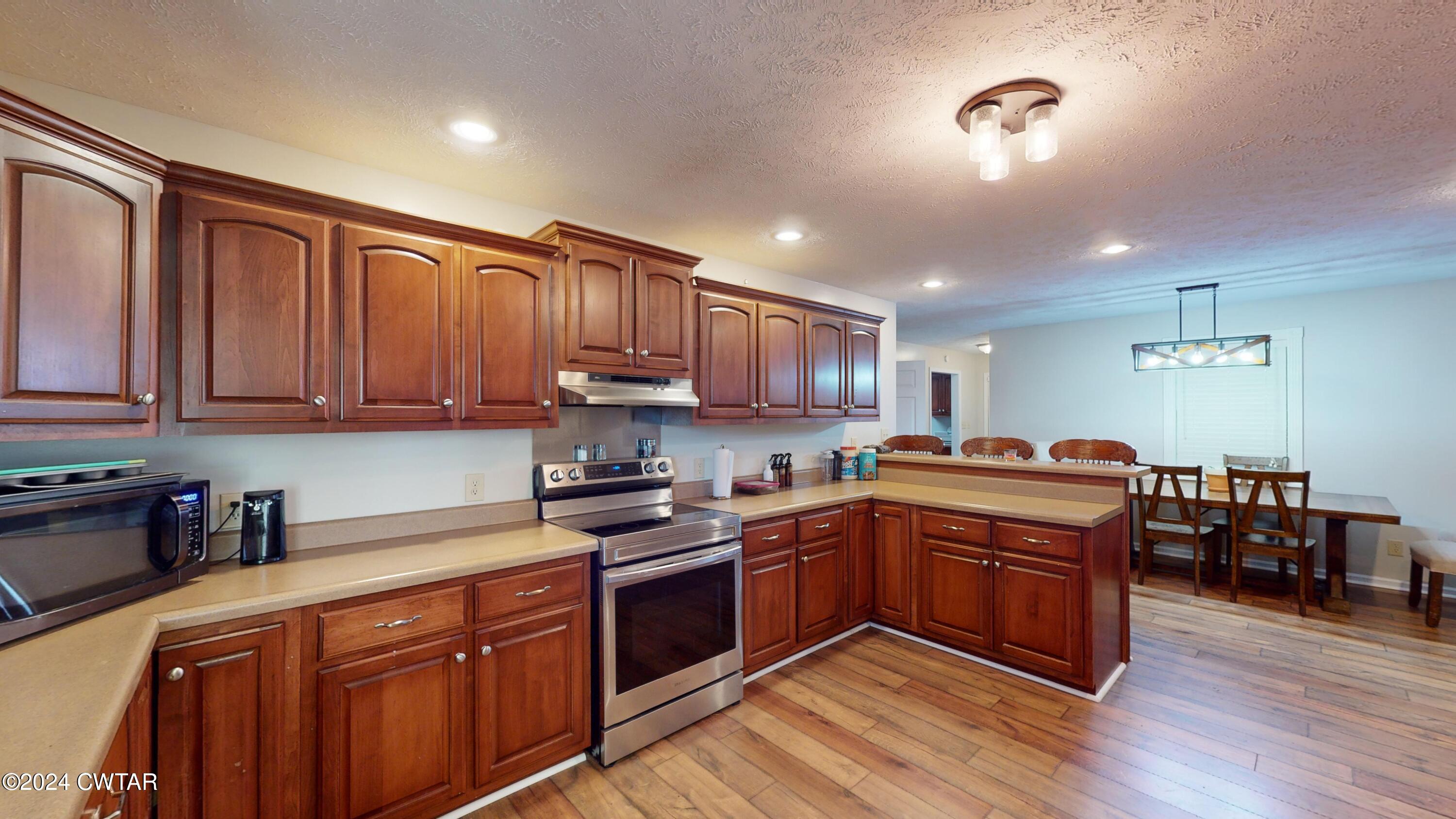 3999 Cloverdale Road Obion, TN 38240 - Photo 13 of 42 a kitchen with stainless steel appliances granite countertop wooden cabinets a sink a stove a refrigerator and island with wooden floor