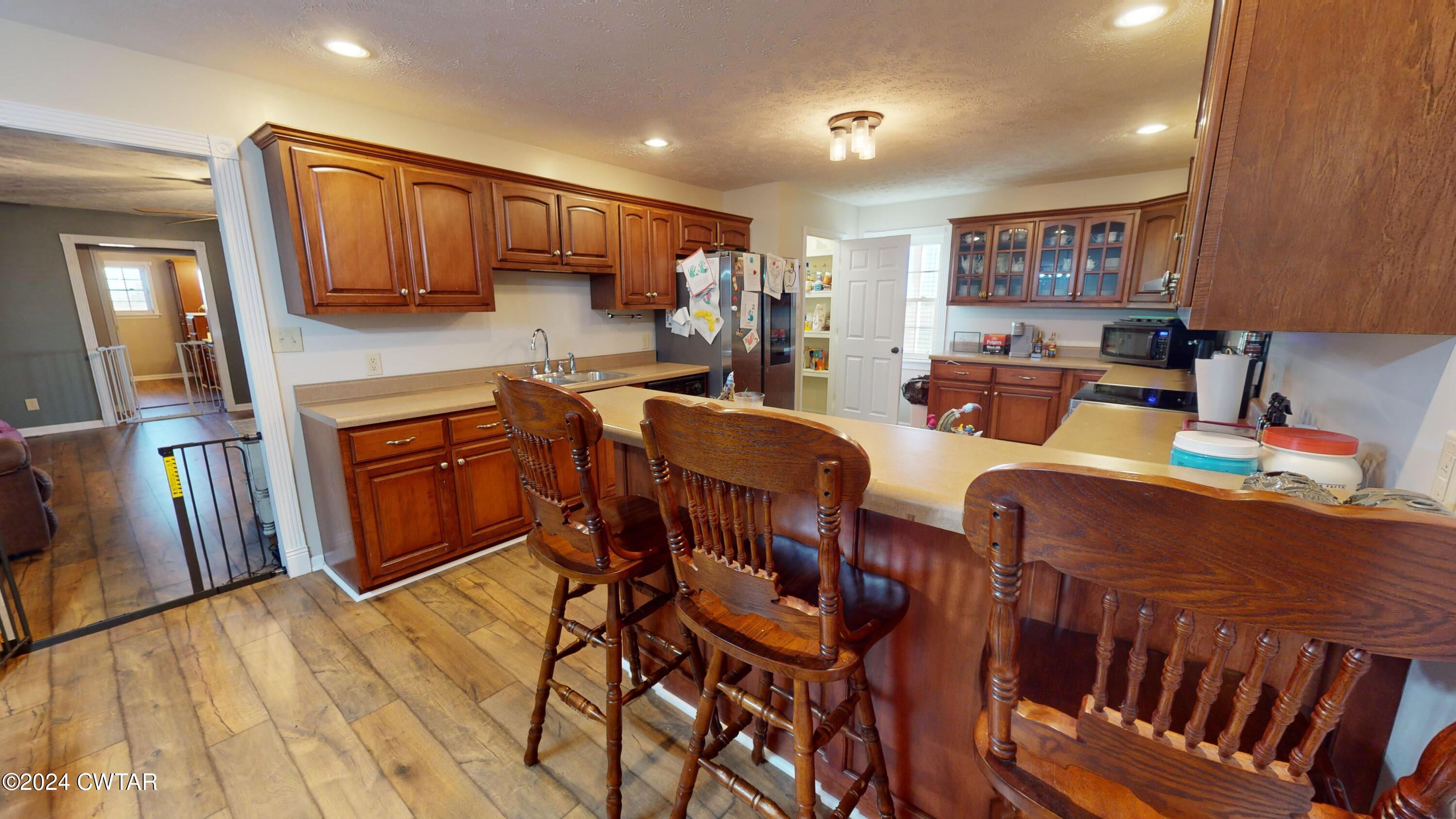 3999 Cloverdale Road Obion, TN 38240 - Photo 8 of 42 a open kitchen with stainless steel appliances granite countertop a refrigerator a stove a sink a dining table and chairs with wooden floor