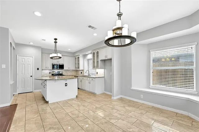 a kitchen with stainless steel appliances granite countertop a stove a sink dishwasher and white cabinets with wooden floor