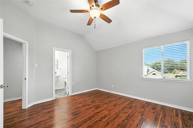 an empty room with wooden floor ceiling fan and windows
