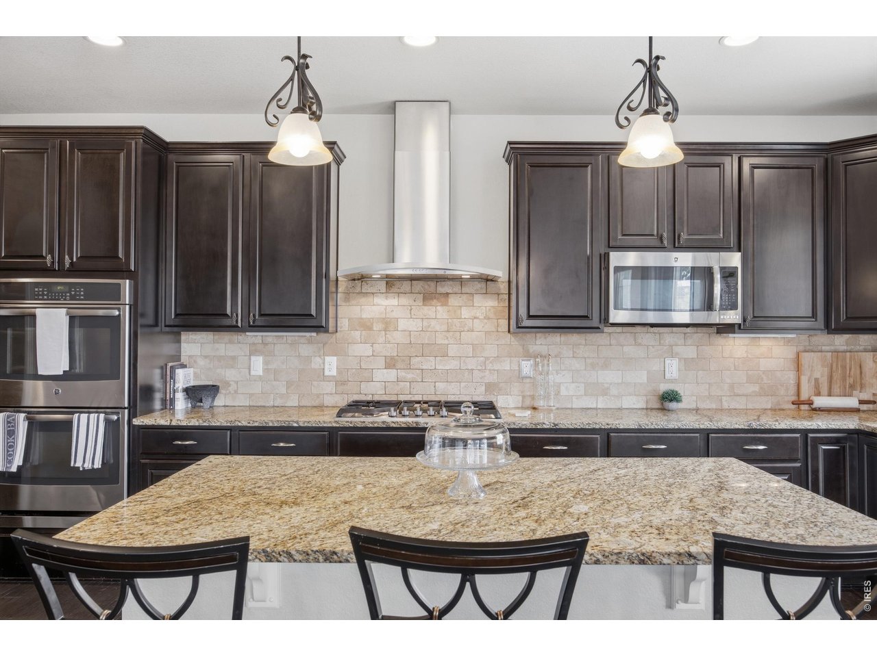 9033 Foxfire Street Firestone, CO 80504 - Photo 12 of 44 a kitchen with stainless steel appliances granite countertop a stove top oven a sink a dining table and chairs