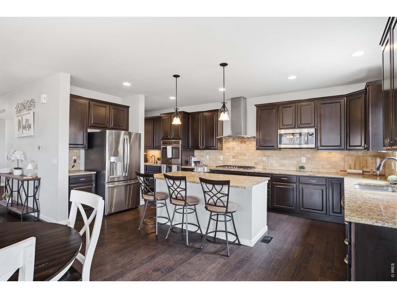 9033 Foxfire Street Firestone, CO 80504 - Photo 13 of 44 a kitchen with stainless steel appliances kitchen island granite countertop a sink refrigerator and cabinets