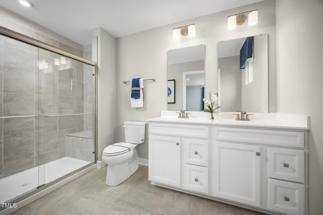 a bathroom with a double vanity sink toilet and shower