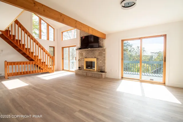 a view of an empty room with wooden floor and a fireplace