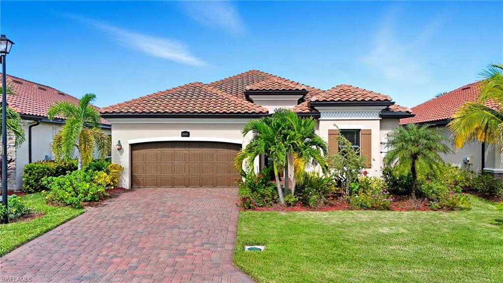 28076 Foxrock Court Bonita Springs, FL 34135 - Photo 2 of 50 Mediterranean style home featuring stucco siding, decorative driveway, 2 car garage, tiled roof, and lush landscaping