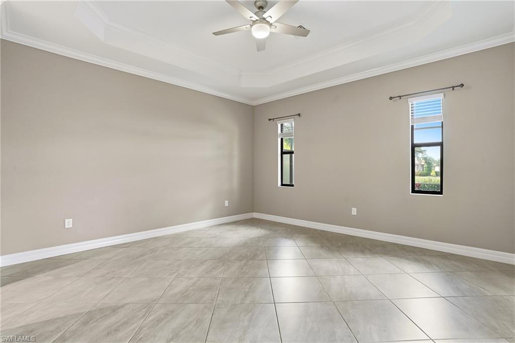 28076 Foxrock Court Bonita Springs, FL 34135 - Photo 26 of 50 Primary bedroom featuring crown molding, custom slider shades w/ remote, tile flooring, tray ceiling, access to outside, and ceiling fan w/ light and controls.