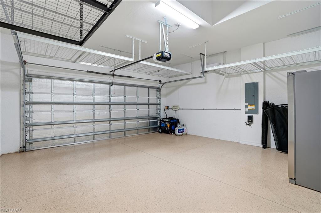 28076 Foxrock Court Bonita Springs, FL 34135 - Photo 38 of 50 Garage featuring freestanding refrigerator, built-in above storage, painted and epoxy garage floor, mini split air conditioner just for the garage, insulated garage door panels, insulated garage attic, wired for a portable generator switch in the electrical panel, and the portable generator.