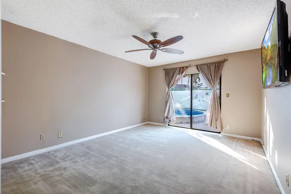 an empty room with windows and ceiling fan