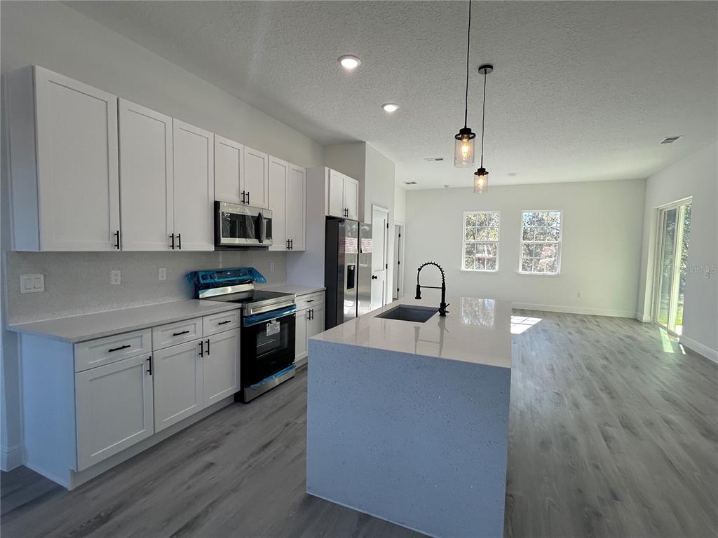 555 Marion Oaks Golf Road Ocala, FL 34473 - Photo 11 of 34 a large kitchen with stainless steel appliances granite countertop a stove a sink dishwasher and a microwave with wooden floor