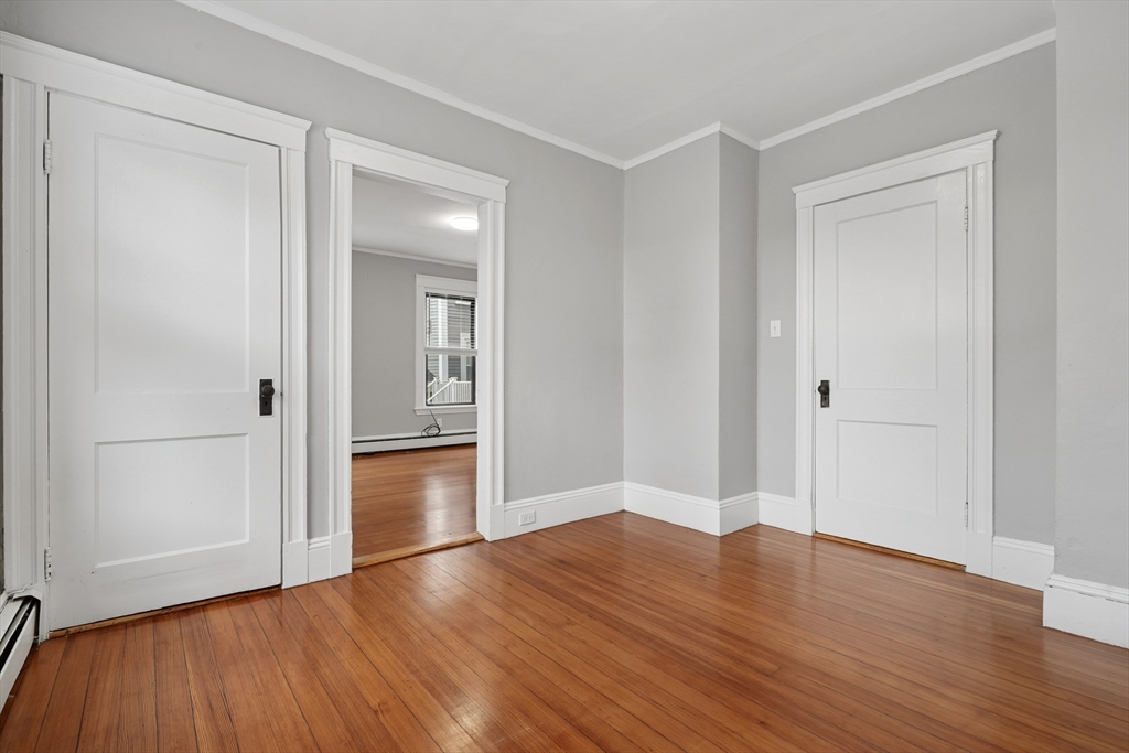 55 Summer Street, Unit 1 Haverhill, MA 01830 - Photo 10 of 13 an empty room with wooden floor & cabinet and windows