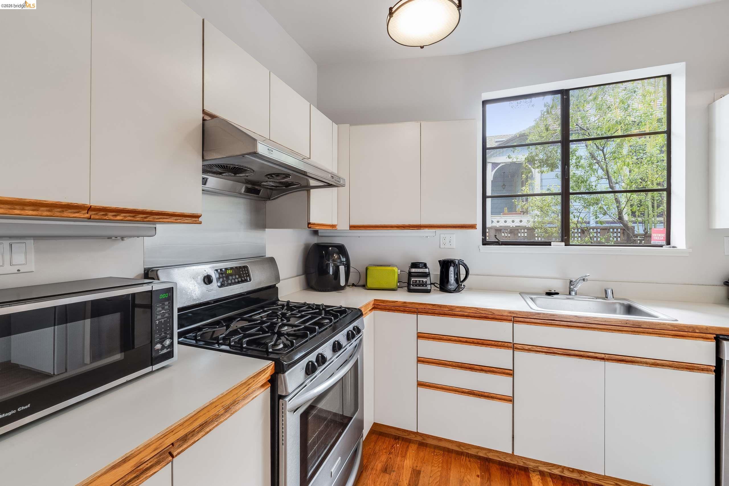 2316 Blake Street, Unit A Berkeley, CA 94704 - Photo 13 of 30 Dual tone kitchen featuring light countertops, stainless steel appliances, dual tone cabinetry, and light wood-type flooring