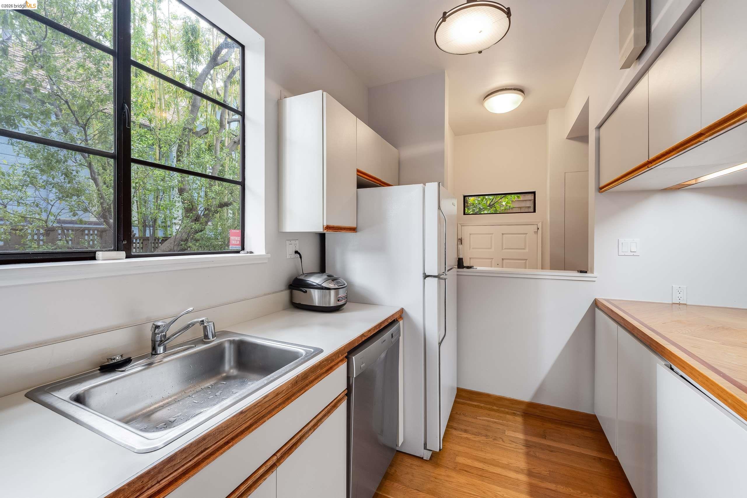 2316 Blake Street, Unit A Berkeley, CA 94704 - Photo 14 of 30 Two tone kitchen featuring light countertops, dishwasher, light wood-style floors, dual tone cabinetry, and freestanding refrigerator