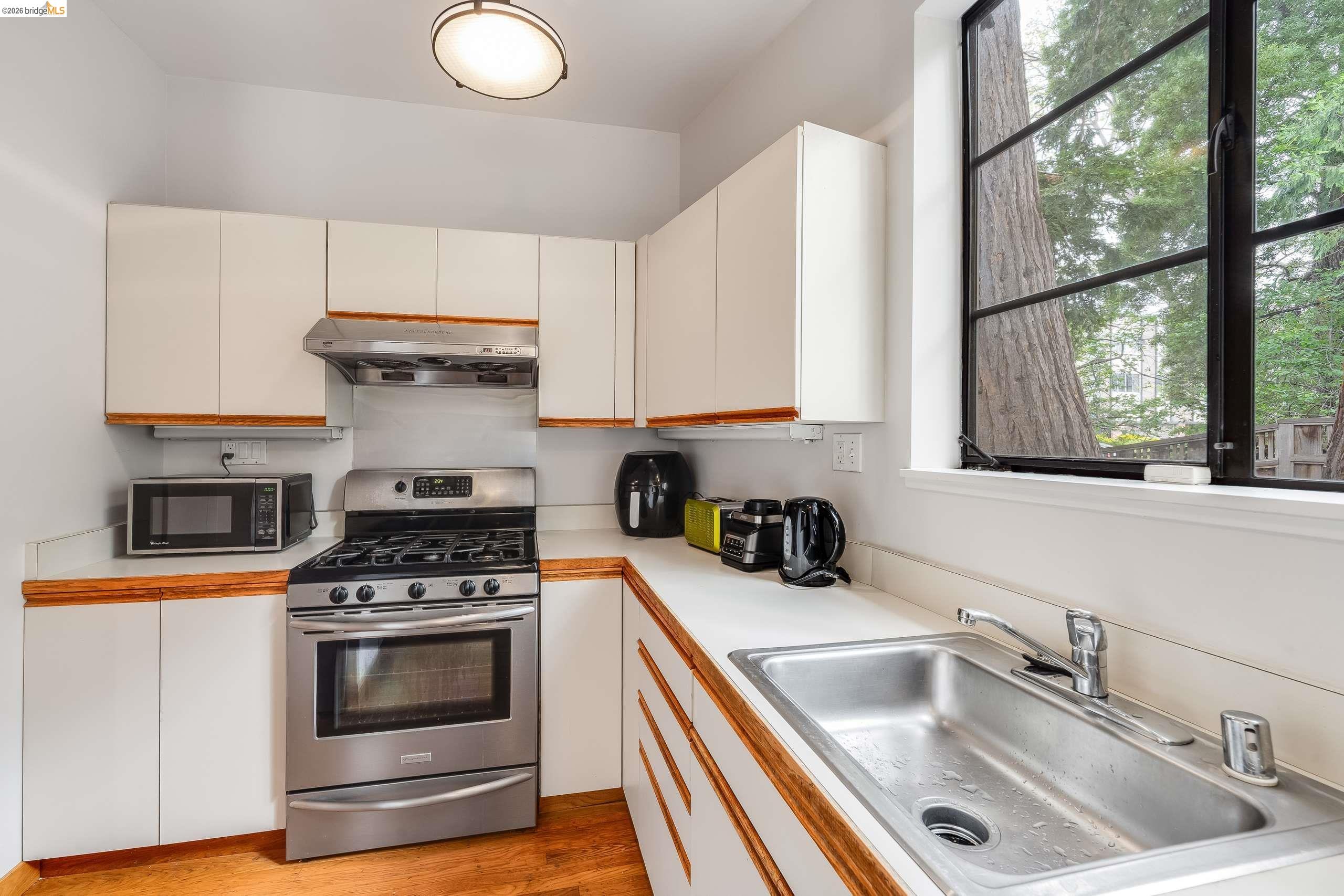 2316 Blake Street, Unit A Berkeley, CA 94704 - Photo 15 of 30 Dual tone kitchen with stainless steel range with gas cooktop, light countertops, light wood finished floors, and two tone color scheme