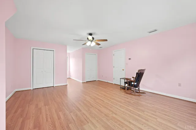 an empty room with windows and ceiling fan