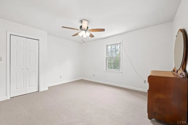 an empty room with a chandelier fan and windows