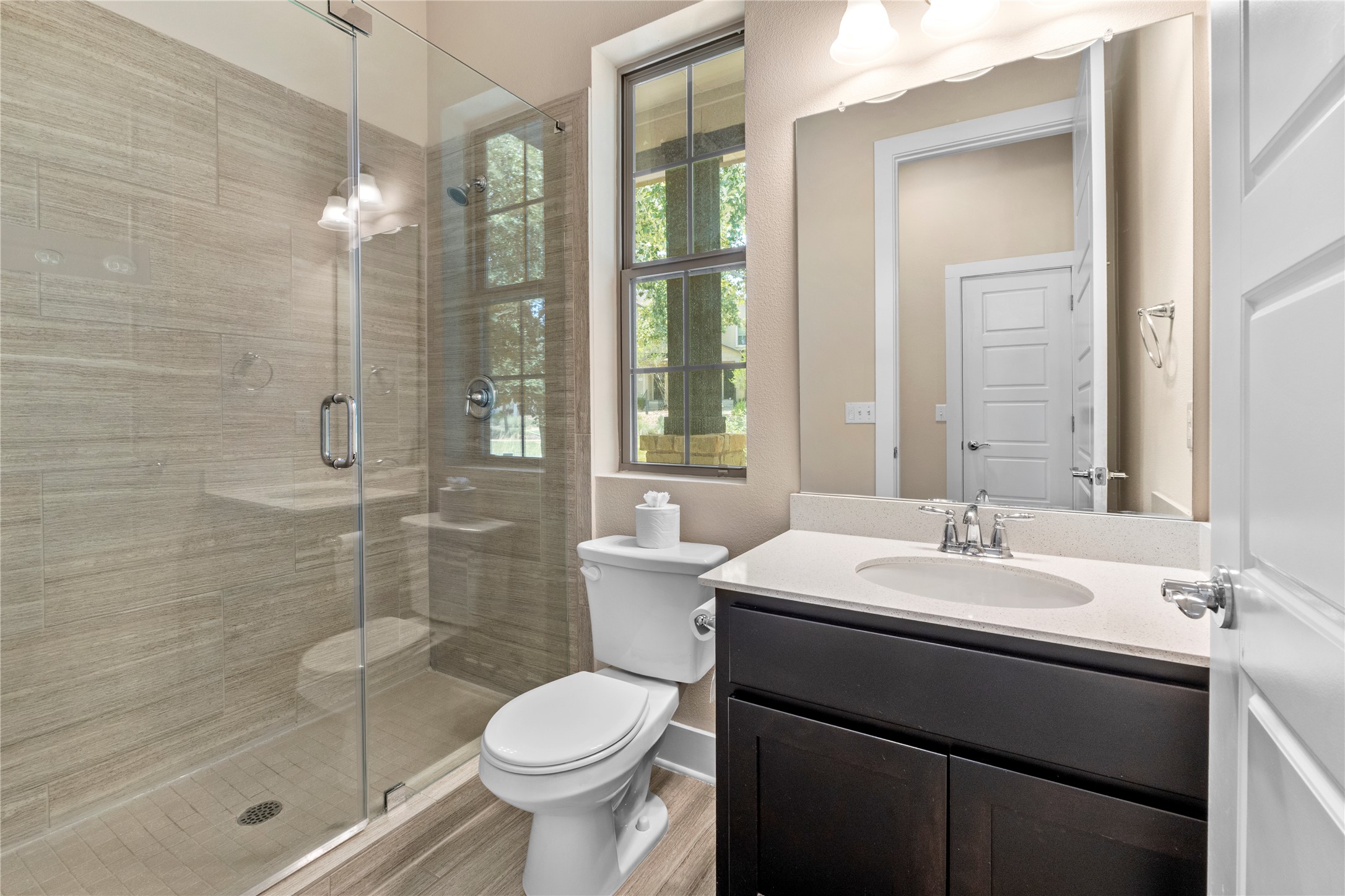 1709 Lawrence Street, Unit 5 Austin, TX 78741 - Photo 18 of 40 Tiled walk-in shower highlights this bathroom with stone countertops and wood-look flooring.