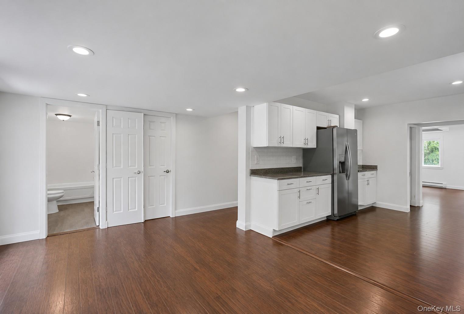 2374 Bruynswick Road Wallkill, NY 12589 - Photo 11 of 35 Wood-finish flooring throughout, recessed lighting, white kitchen cabinetry with stainless steel appliances, and a tiled backsplash