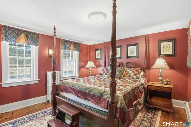 a bedroom with a bed wooden floor and window