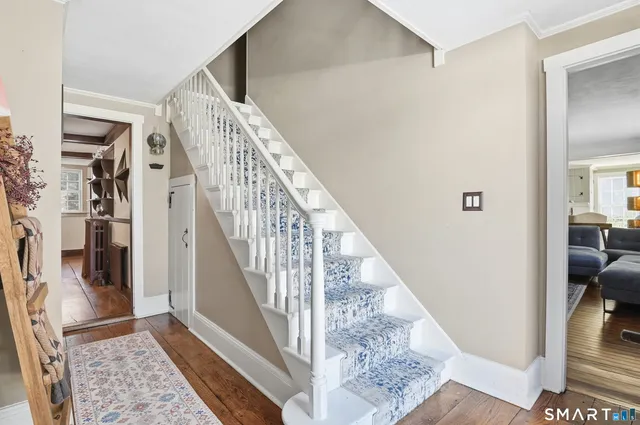 a view of staircase with white walls and a rug