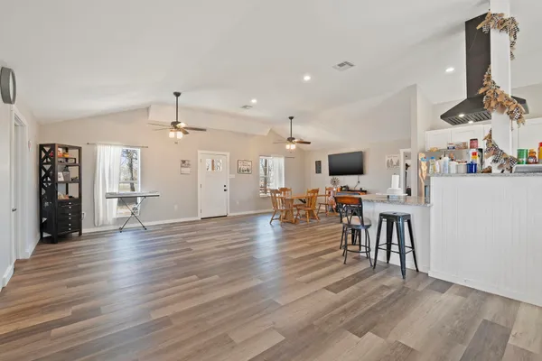 a dining room with wooden floor a chandelier a wooden table and chairs