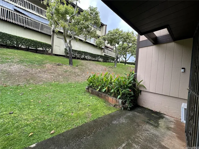 a view of a house with a yard and a bench under an umbrella