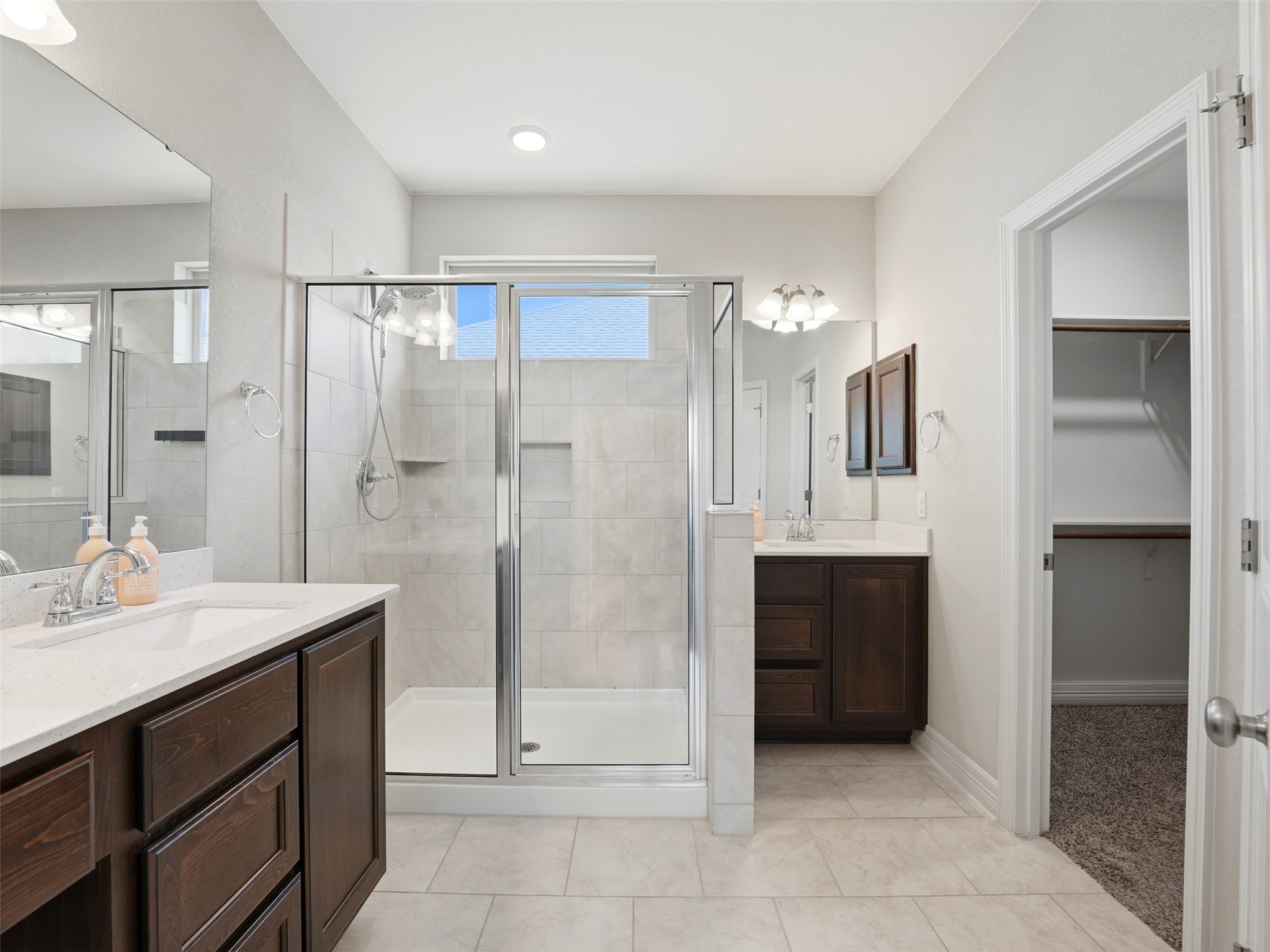 2132 Ringstaff Road Leander, TX 78641 - Photo 24 of 39 Dual vanities and a spacious shower elevate this primary bathroom's functional design.